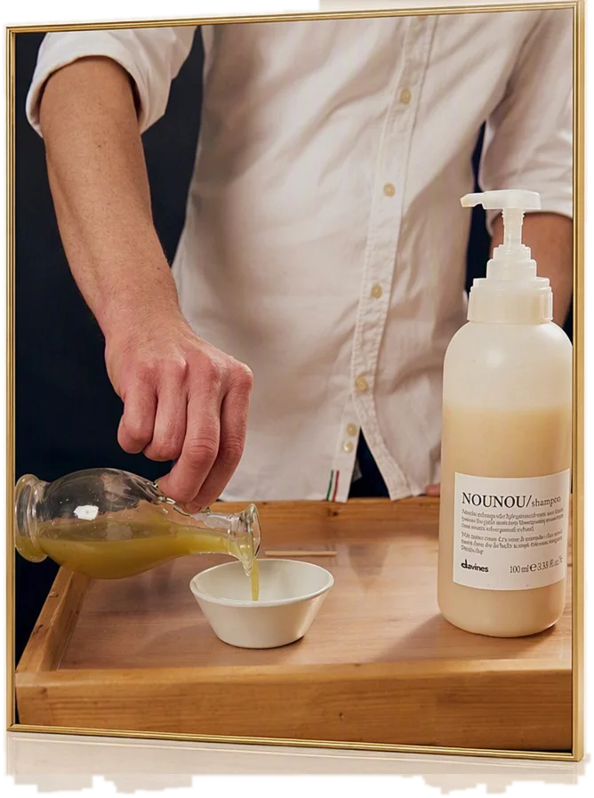 Mirko versa il succo d’aloe dalla caraffa in una ciotola, accanto al flacone Davines NOUNOU